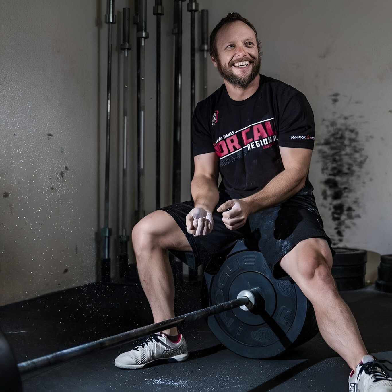 Jason sitting on bumper plates smiling